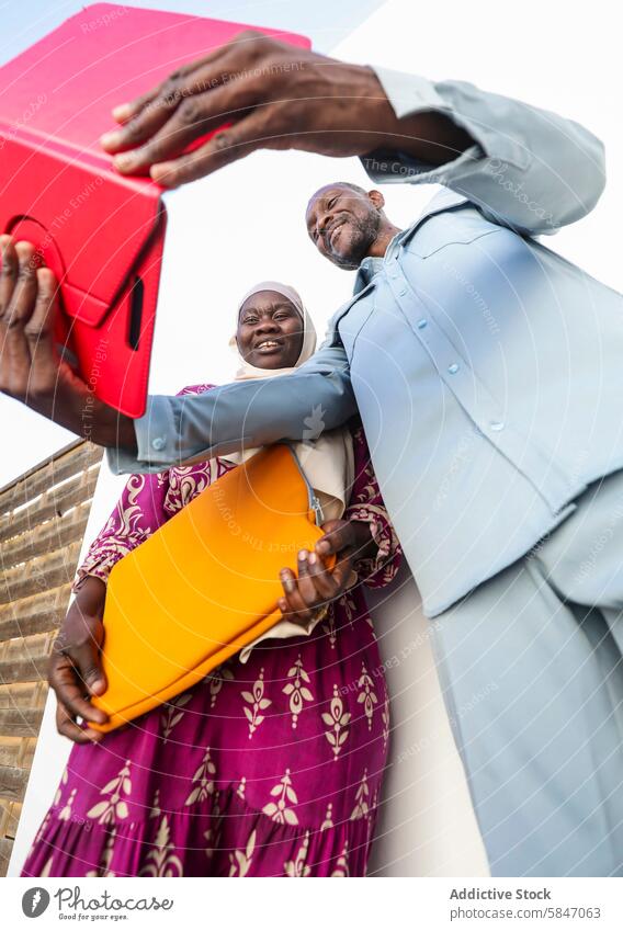 Joyful couple sharing gifts under a clear sky exchange happiness smiling man woman outdoor bright summer cheerful meeting colorful ethnic joy togetherness