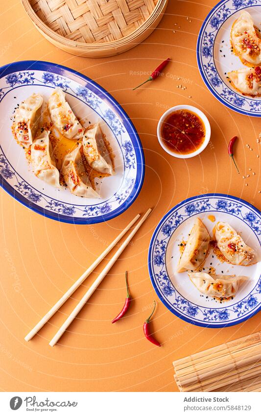 Traditional Chinese dumplings served in ornate blue plates asian food Culinary Serving appetizer authentic bamboo steamer chili dip chili sauce chopsticks