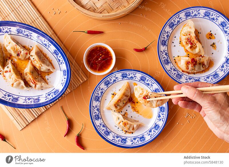 Delicious Asian dumplings served with spicy dipping sauce asian food Culinary Serving bamboo steamer blue and white plates chili dip chili sauce chopsticks