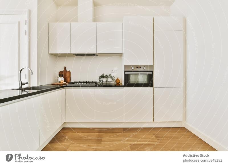 Sleek Modern Kitchen with White Cabinets and Wooden Flooring kitchen modern white cabinet wooden floor sleek minimalist decor countertop black built-in oven