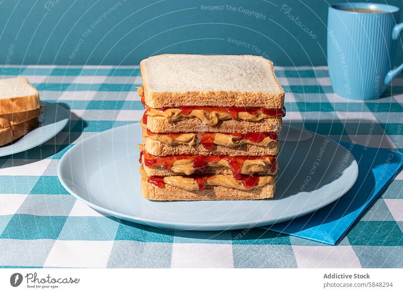 Peanut Butter and Jelly sandwich served on a blue plate , a cup of an american coffee and some bread slices in a blue background BREAD BREAKFAST FOOD HEALTHY