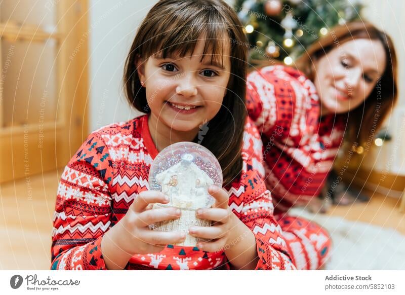 Family joy with Christmas snow globe mother christmas family little girl woman mom celebration smiling festive sweater holiday child daughter adult smile home