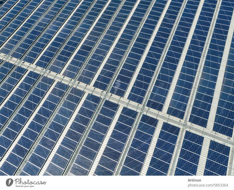 Solar panels on roof of industrial plant. Solar energy for factory or warehouse building. Commercial solar. Industrial photovoltaic panels. Rooftop solar power. Green energy. Sustainable energy.