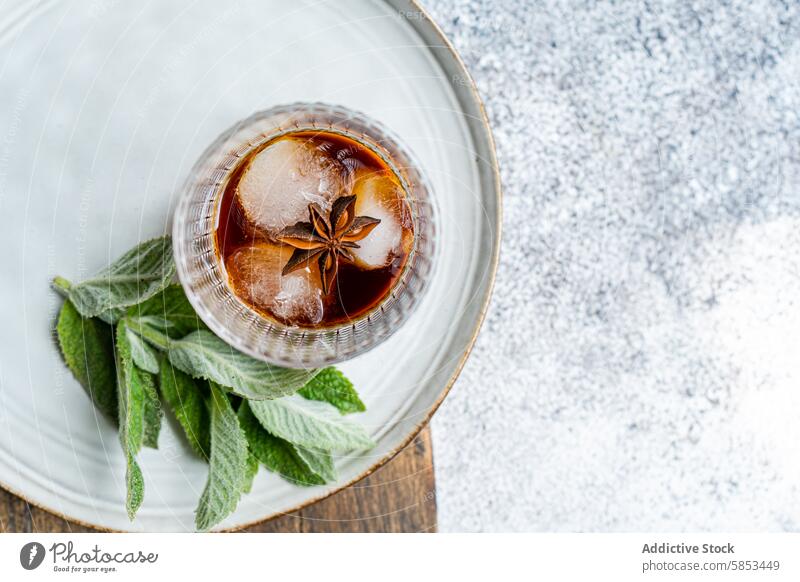 Top view of cherry cocktail with ice and mint on a plate beverage top view drink rustic star anise garnish refreshing summer alcohol mixology glass cold