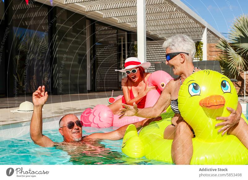 Joyful seniors enjoying pool time with inflatables swimming pool fun duck ring laughing sunny outdoor leisure recreation water summer happiness elderly swimwear