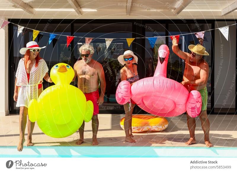 Joyful seniors celebrating with pool floats fun swimming pool party celebration inflatable duck flamingo banner festive leisure retirement summer outdoor