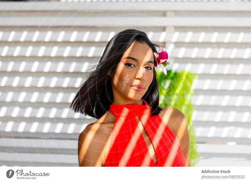 Elegant woman with tropical flower in red dress elegant hair pose background pattern vibrant lady fashion style chic beauty attractive portrait femininity