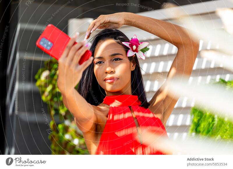 Lady in Red Capturing Selfie Moment with Phone woman red dress selfie smartphone flower hair elegance style beauty fashion vibrant camera posing tropical