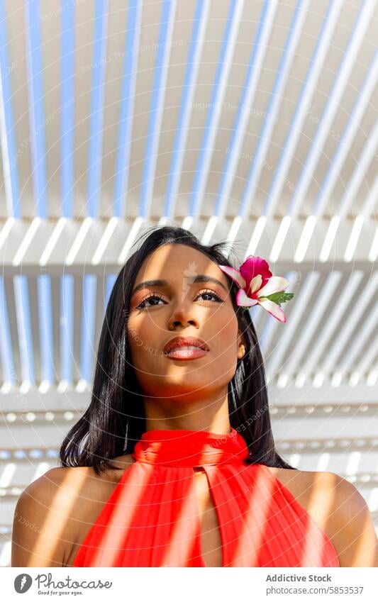 Elegant lady in red dress with a flower woman elegant hair modern background vibrant delicate standing fashion style beauty outdoor daylight feminine chic pose