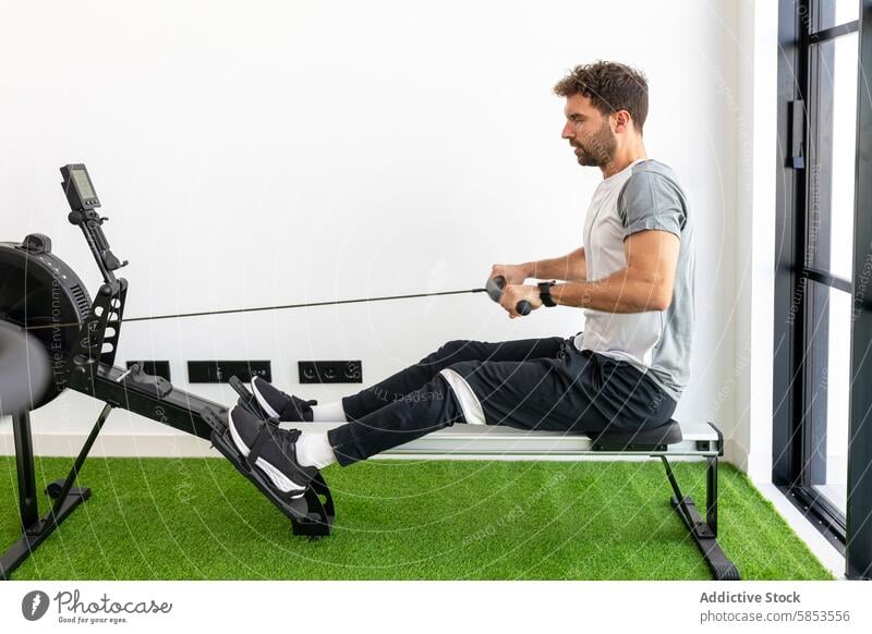 Man exercising on a rowing machine in a modern gym man exercise workout fitness athlete health indoor equipment sport training strength muscular endurance