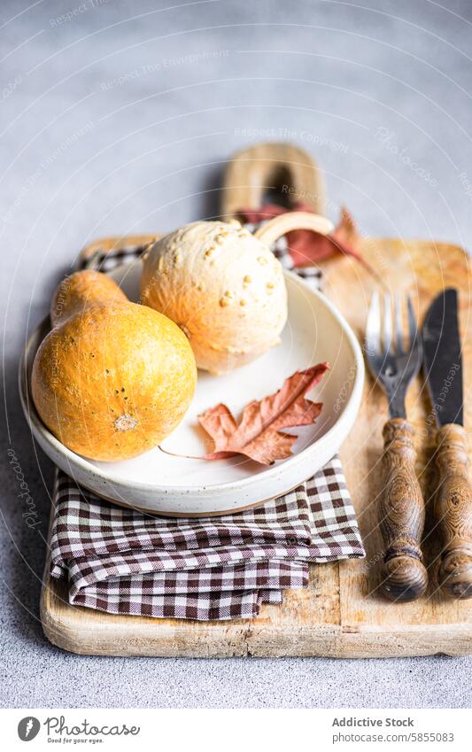 Seasonal autumn display featuring pumpkins and leaf gourd wooden board rustic vintage cutlery napkin seasonal cozy flat lay tableware texture nature harvest