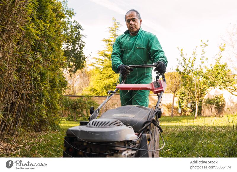 Man mowing lawn in a sunny backyard garden man mower lawnmower outdoor maintenance senior uniform green grass landscaping work gardening activity nature