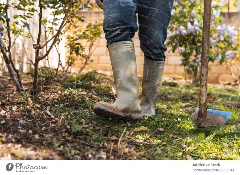 Gardener working outdoors wearing rubber boots with a shovel garden gardening gardener digging soil plants foliage yard labor nature standing jeans dirty rustic