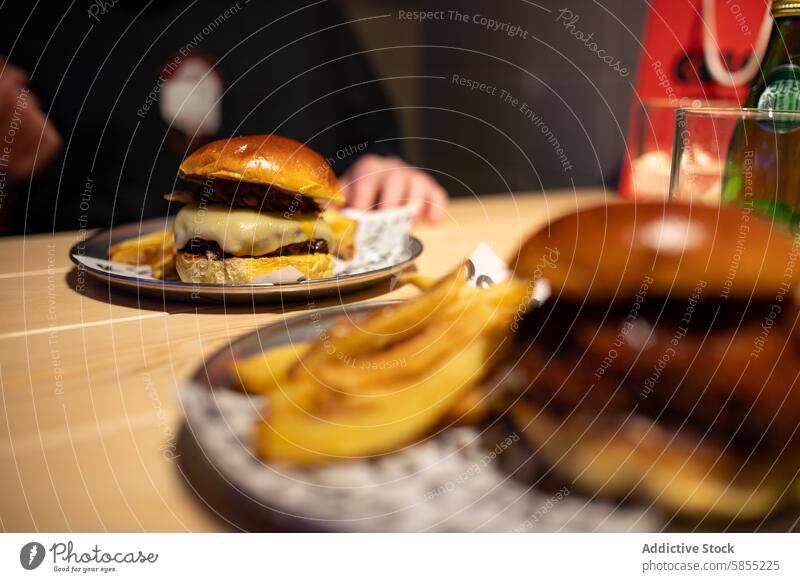 Juicy cheeseburger and fries served on a restaurant table food meal bun beef fast food casual dining plate cuisine delicious tasty juicy golden contemporary