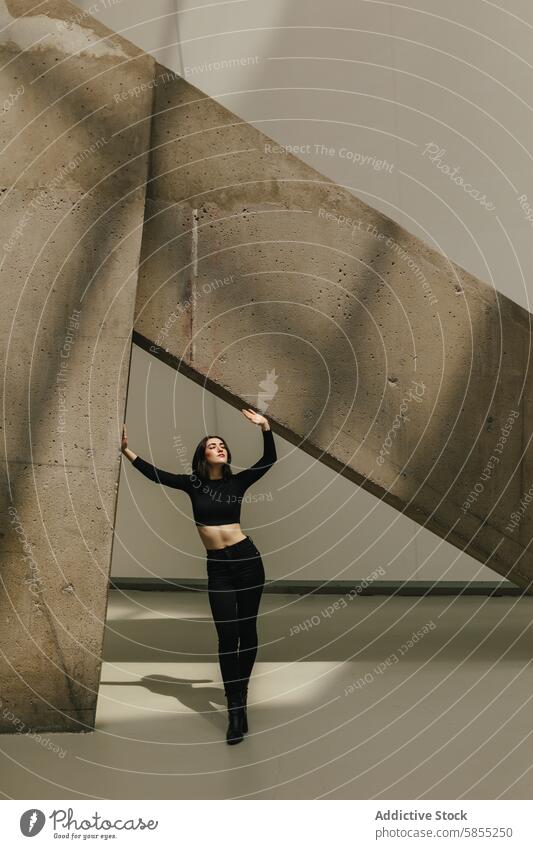 Woman posing artistically under concrete architecture woman pose modern urban environment structure geometric aesthetic young fashion style angle sunlight