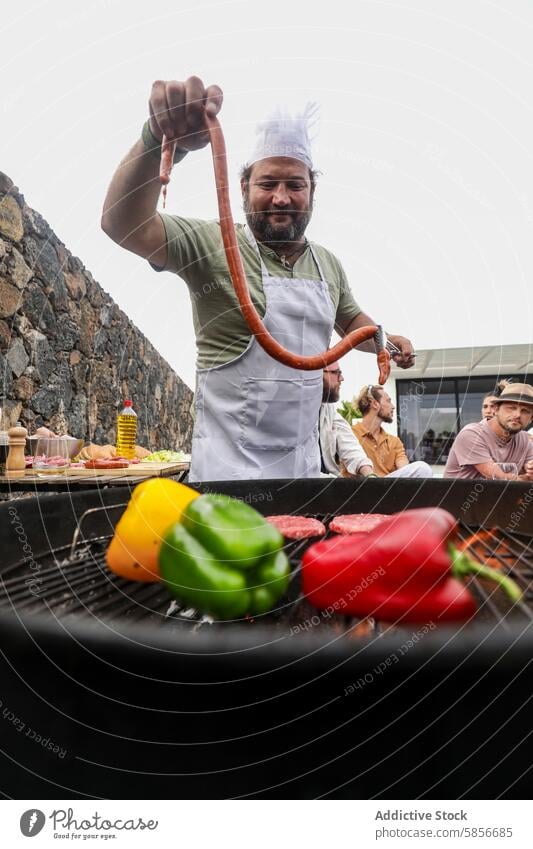 Chef grilling at outdoor BBQ with diverse group of friends bbq chef sausage meat multiethnic conversation casual friendly apron chef hat cooking summer