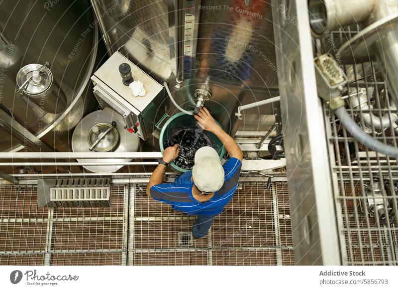 Winery worker managing fermentation tanks from above winery supervision top-down view production tradition craft careful industry vintner stainless steel