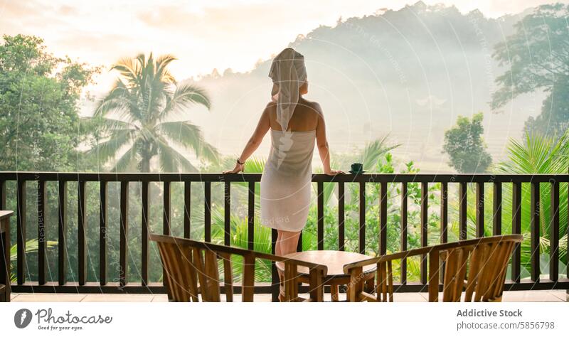 Woman in towel enjoying serene tropical mountain view woman balcony palm tree tranquil morning mist scenic lush greenery relaxation peace escape travel vacation