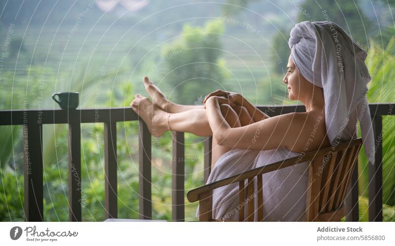 Woman in towel enjoying morning on tropical balcony woman coffee nature peaceful serene lush greenery mountain view chair wood relaxation tranquil environment