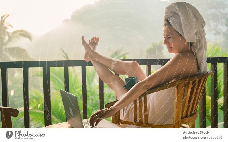 Relaxing morning with laptop on tropical balcony woman coffee relaxation greenery peaceful work leisure towel outdoor nature technology serene cozy remote work