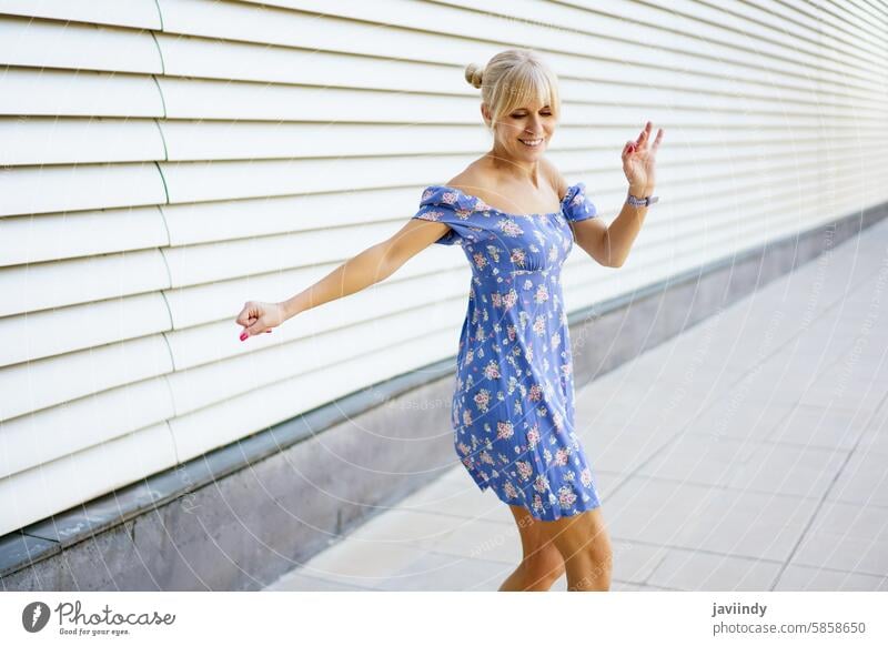 Sensual woman in summer dress dancing music in the city sensual blonde happy modern urban joyful energetic stylish fashion movement expressive street fun