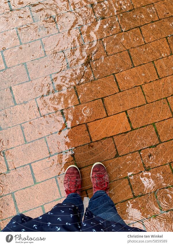 On foot in rainy weather Rain Puddle Wet wet shoes Raincoat raindrops Rainy weather Bad weather Reflection off Paving stone paved Red Blue on foot drenched