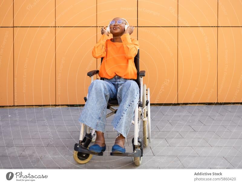 Cheerful woman in wheelchair enjoying sunny day outdoors disabled joyful vibrant orange fashion accessible independence wheelchair user city cause disability