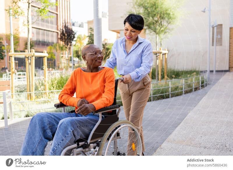 Professional woman assists colleague in wheelchair outdoors businesswoman latin woman african american black woman inclusion assistance support urban