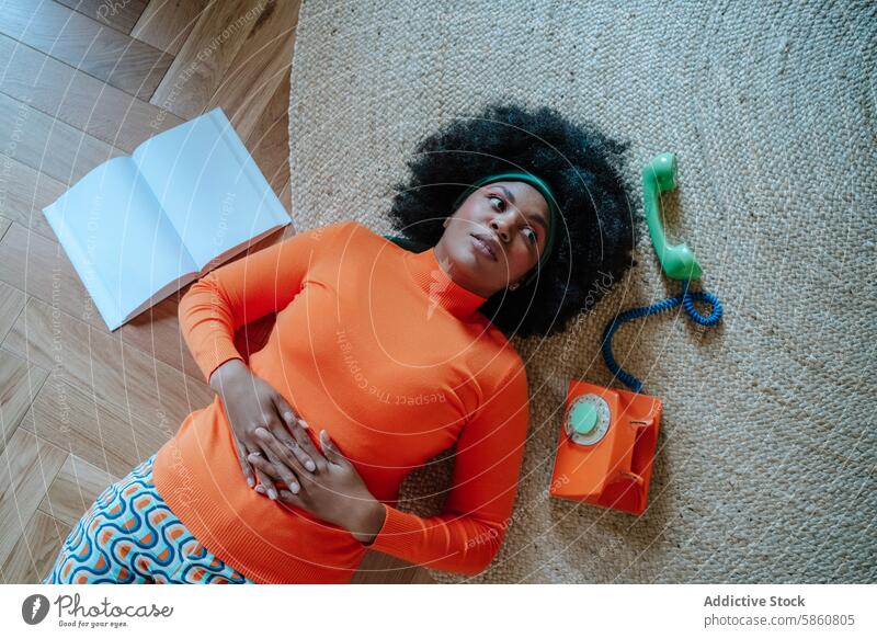 Woman in orange with vintage phone looks away woman black sweater skirt floor telephone green looking away carpet wood retro belly concept housewife 50s fashion