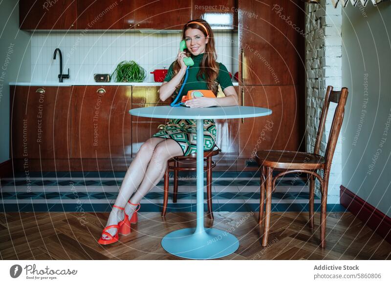 Vintage-style housewife chatting on a retro phone in the kitchen vintage telephone 1950s woman nostalgic smile outfit table sitting happy green dress home