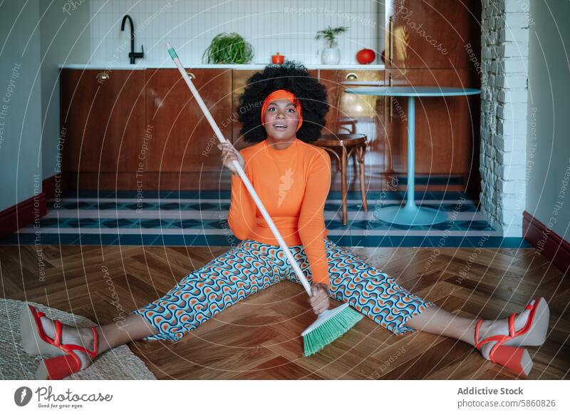 Retro housewife in vibrant attire humorously sweeping floor with broom woman black african american retro 50's split expression indoor surprised cleaning