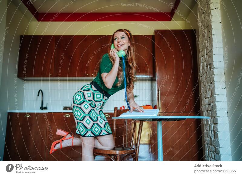 Playful 1950s housewife chatting on phone while ironing woman retro telephone kitchen caucasian fashion vintage hairstyle smile happy conversing redhead