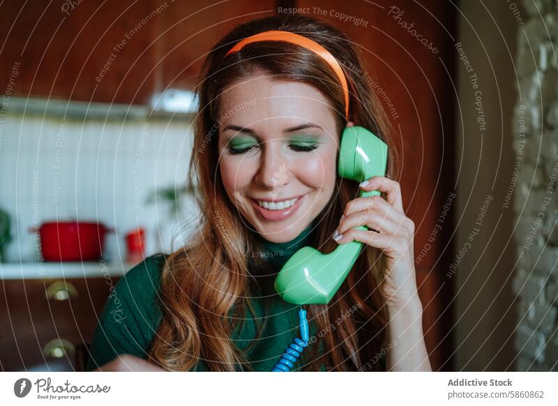 Woman in 1950s style using an old rotary phone and smiling woman kitchen vintage eyes closed playfully smile conversation engaging happy green phone redhead