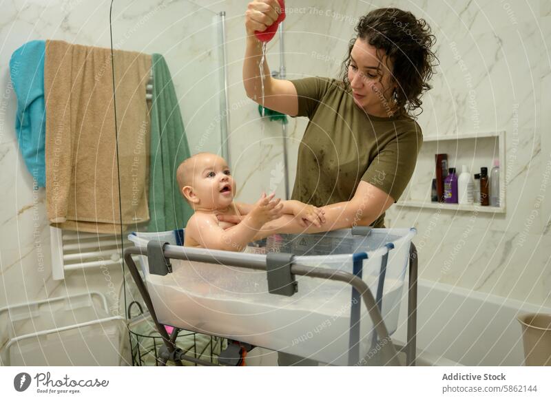 Joyful baby bath time with mom in a modern bathroom mother water toy smile caucasian infant happy playful care motherhood parenting child family interaction