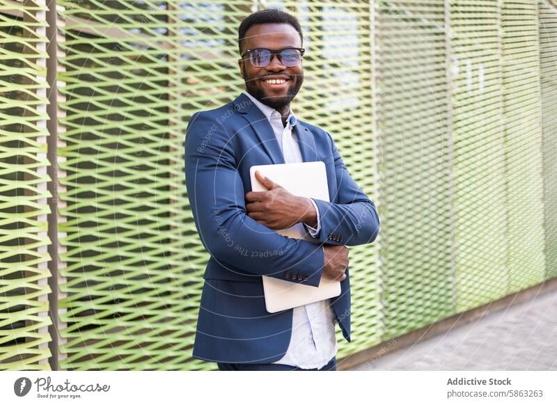 Confident African American businessman holding a laptop african american smiling looking at camera blue suit confident stylish male professional technology