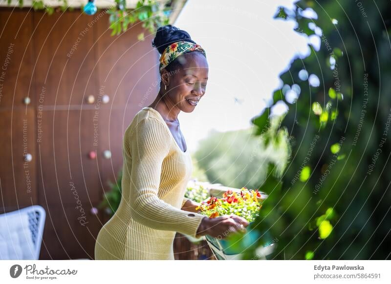 Beautiful woman watering plants on the balcony people joy black natural attractive black woman happiness happy real people mature adult daily life one person