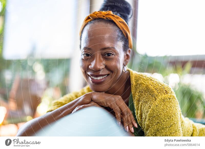 Portrait of smiling woman relaxing on sofa at home, looking at camera people joy black natural attractive black woman happiness happy real people mature adult