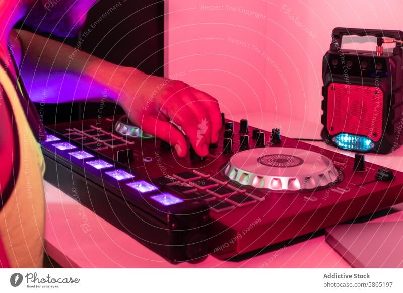 DJ mixing music in a studio with colorful lighting dj console hand knob slider adjust pink purple electronic sound equipment party event performance artist