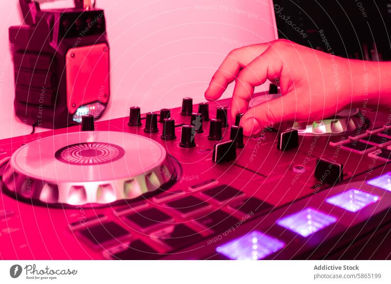 Hand manipulating a DJ controller in a vivid pink light dj hand music technology knob slider illuminate energy modern adjust mixing disc jockey entertainment