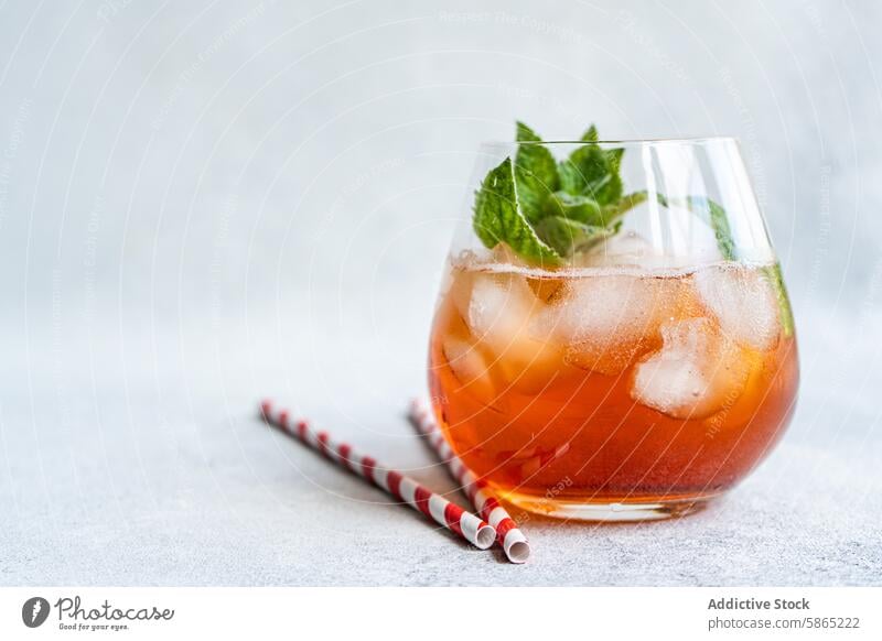 Refreshing coke cocktail with mint and ice in glass beverage straw paper red striped chilled garnish leaves cubes grey background texture refreshing drink serve