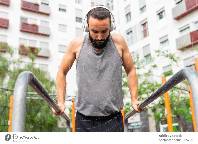 Man exercising outdoors in Poblenou with headphones man exercise poblenou barcelona sleeveless shirt dip parallel bar urban building focus fitness lifestyle