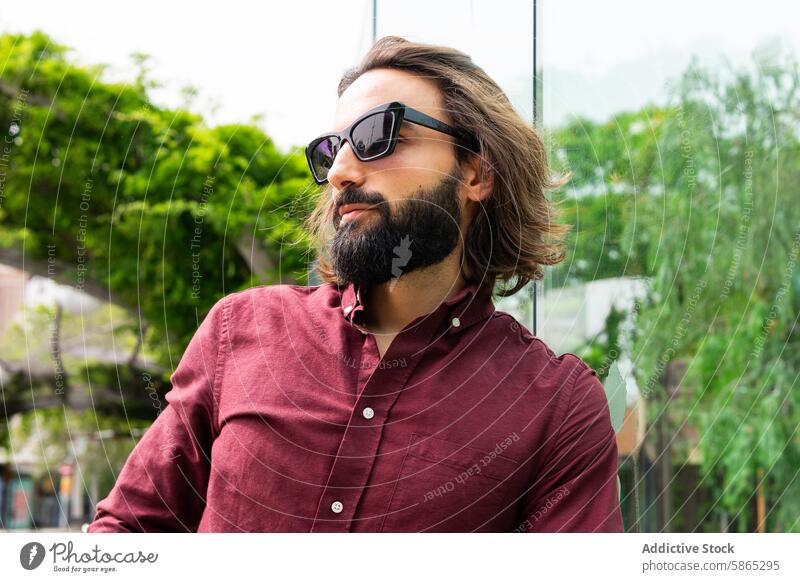 Stylish man in Poblenou with sunglasses and maroon shirt fashion poblenou barcelona lifestyle beard long hair young male casual outdoors sunny day modern trendy