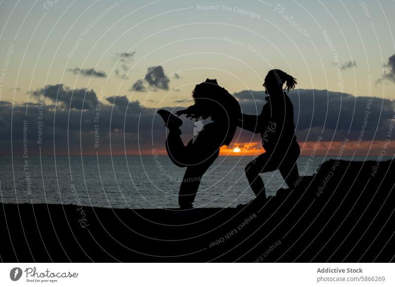 Silhouetted dancers performing against a stunning sunset silhouette male female street dance performance dynamic dreadlocks vibrant background motion action