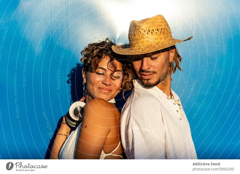 Close-up of a street dancing couple against a blue background street dancer man woman tender moment smile look down straw hat dreadlocks eyes closed headphones