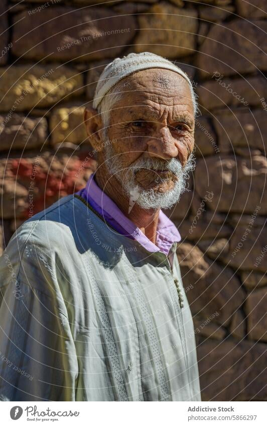 Elderly Moroccan man in traditional attire against stone wall morocco north africa elderly cap rustic portrait culture age wisdom serenity mature authentic