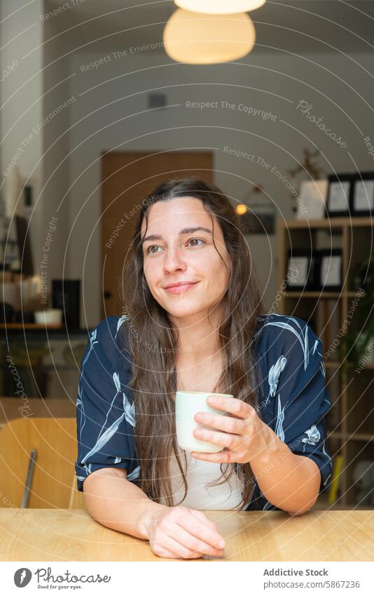 Woman enjoying a coffee break at a modern cafe woman looking away cup casual floral blouse relaxation thoughtful bright indoor sitting table drink beverage