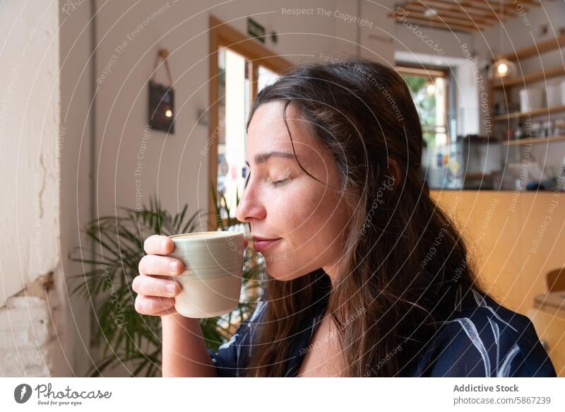 Young woman enjoying coffee in a cozy cafe cup drink ceramic relax sunlight morning sipping casual refreshment beverage break leisure female adult quiet serene