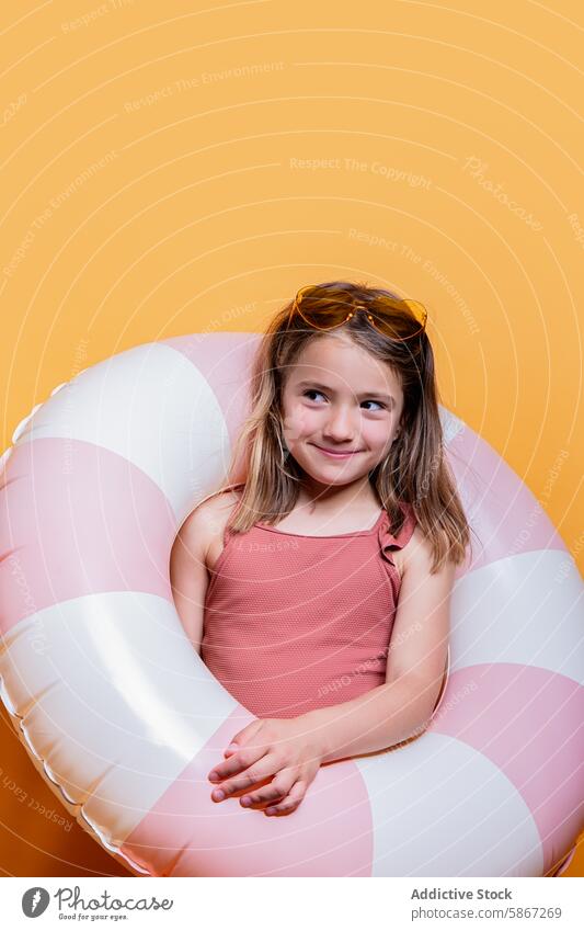 Girl in summer theme with inflatable ring in studio girl orange background sunglasses dress smile joy child sunny photo portrait happy playful leisure vacation