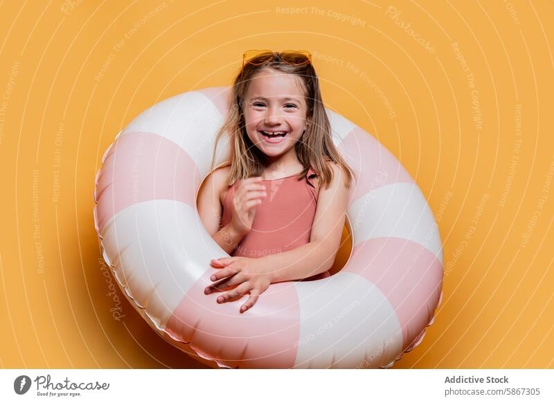 Cheerful child with float ring in summer studio setup swimsuit sunglasses yellow background cheerful joy happiness playful girl young bright leisure vacation