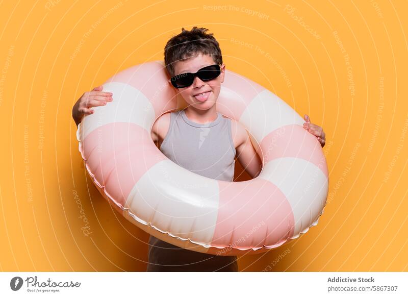 Young boy with swim ring in a summer-themed studio shoot sunglasses orange background playful cheerful youth happiness fun leisure vacation child